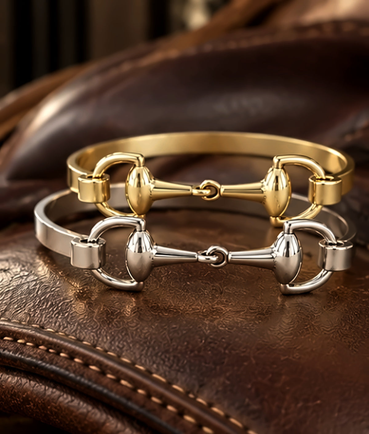 Silver and gold snaffle bit bracelets stacked together on a leather saddle